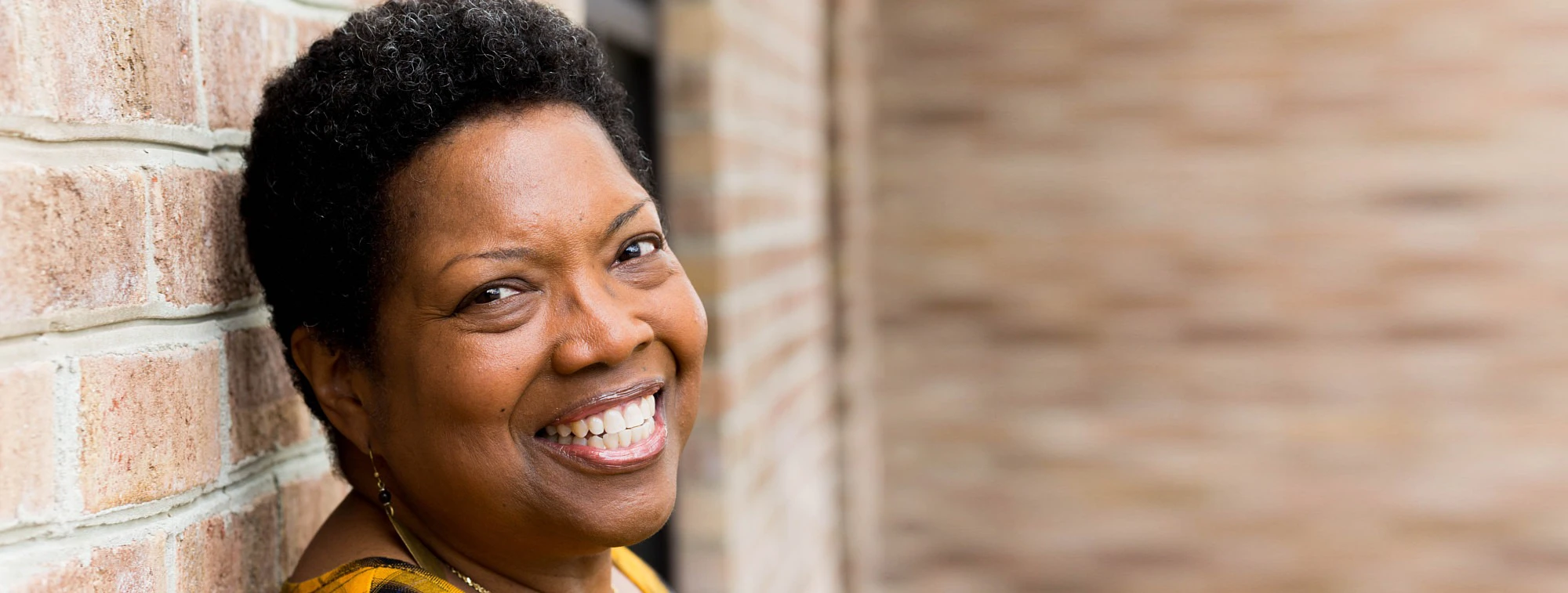 Happy Patient Smiling Leaning Against Brick Wall