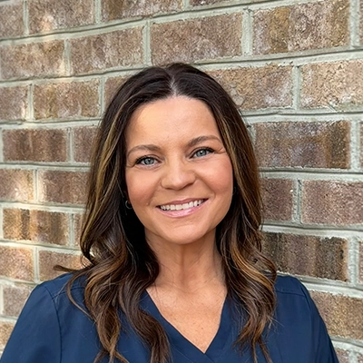 Orthodontic Assistant Manda Whitehurst Smiling In Front Of Brick Wall